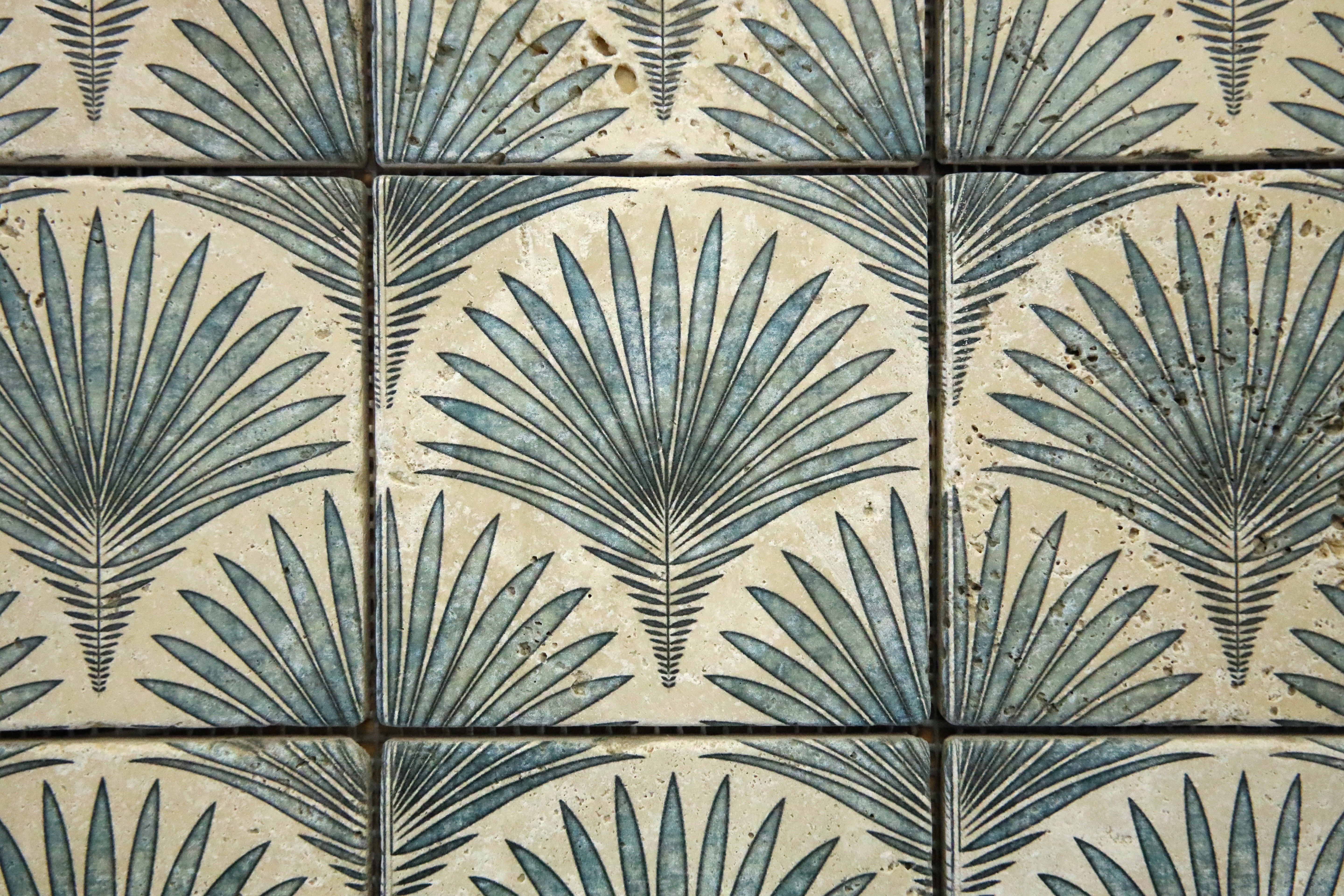 Close-up detail of palm-inspired digital pattern on tumbled travertine mosaic tile
