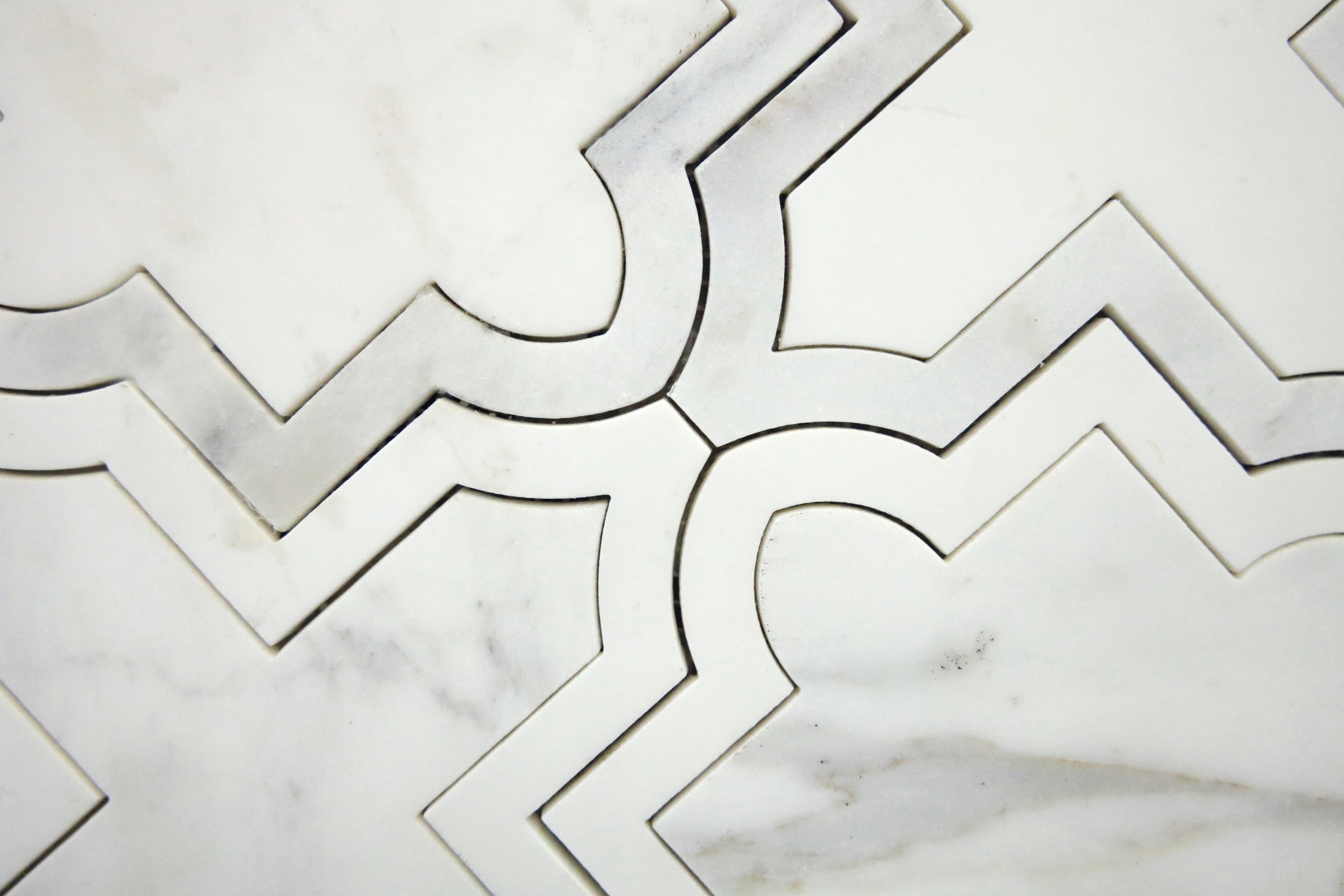 Geometric white marble mosaic tile with curved waterjet-cut pattern detail