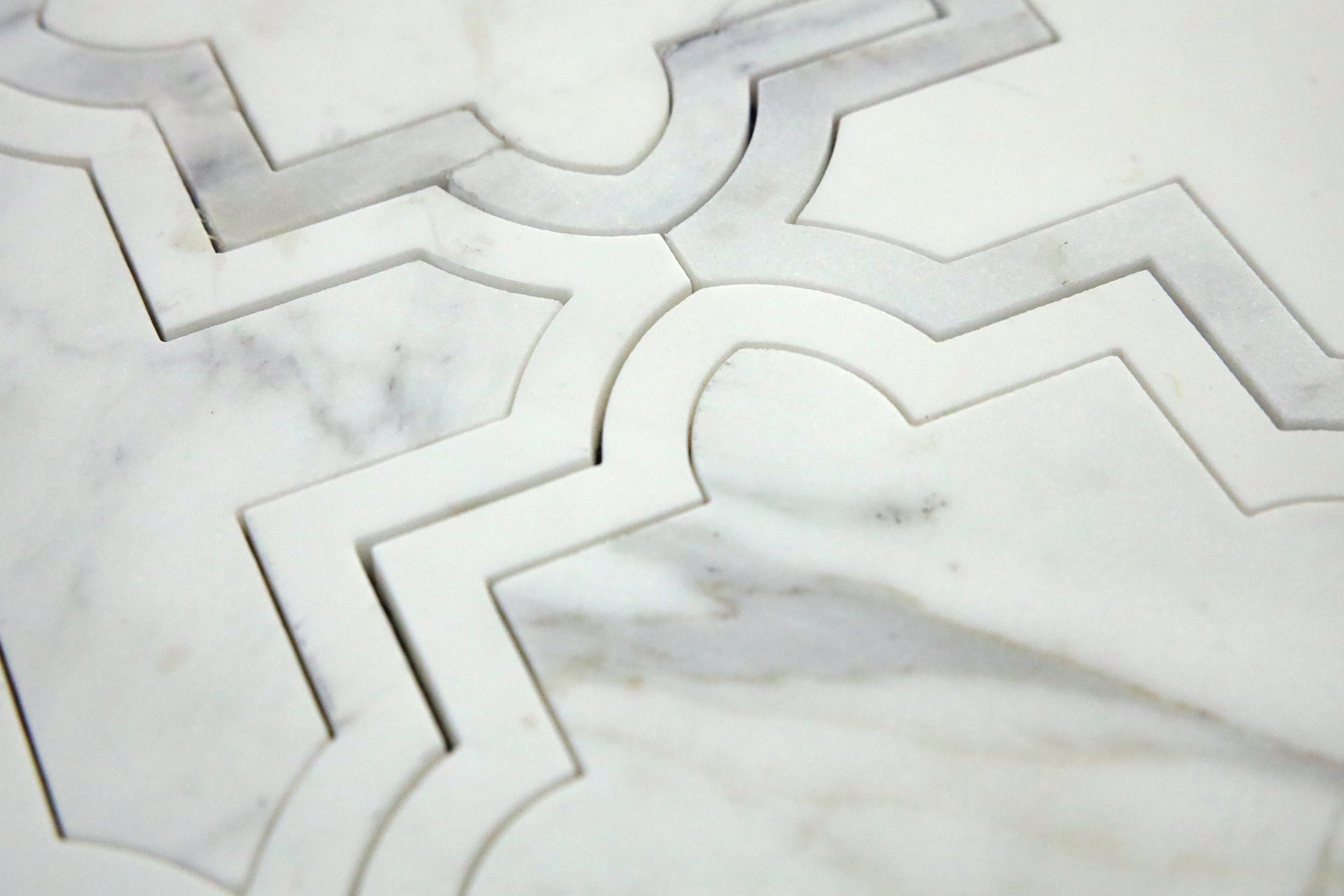 Close-up of honed white marble waterjet mosaic showing geometric detailing